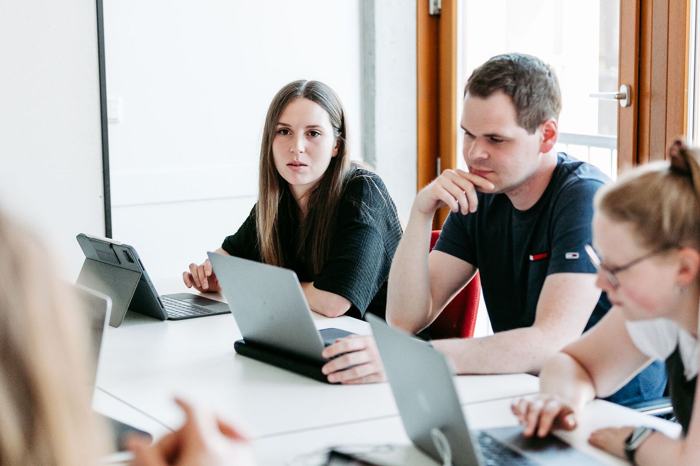 Drei Menschen sitzen an ihren Laptops und besprechen sich